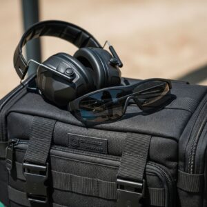 range bag with electronic earmuffs and shooting glasses resting on top